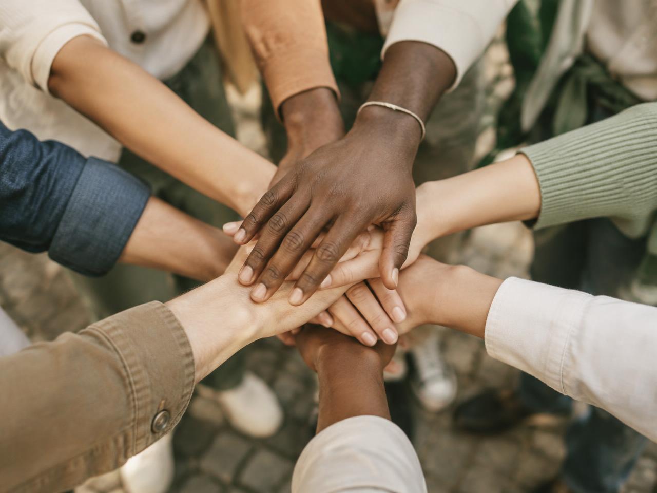 Hands of many different people stacked together in a team huddle